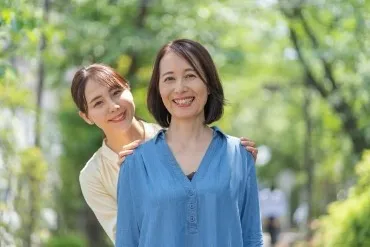 カウンセリング　万引き　夜尿症　お母さんの肩に手を当てて笑顔の娘